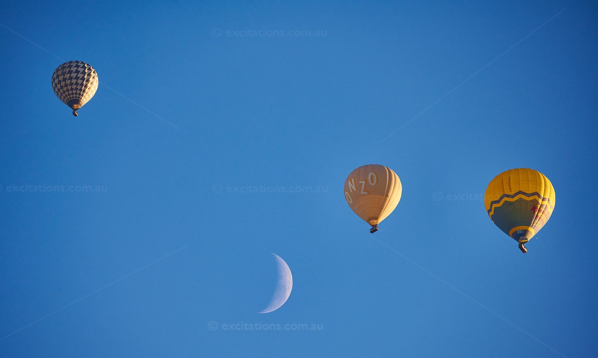 A group of 3 Global Ballooning hot air balloons with the moon in shot, appearing as if they are flying with the moon. NO AI, real photo. © excitations.photography